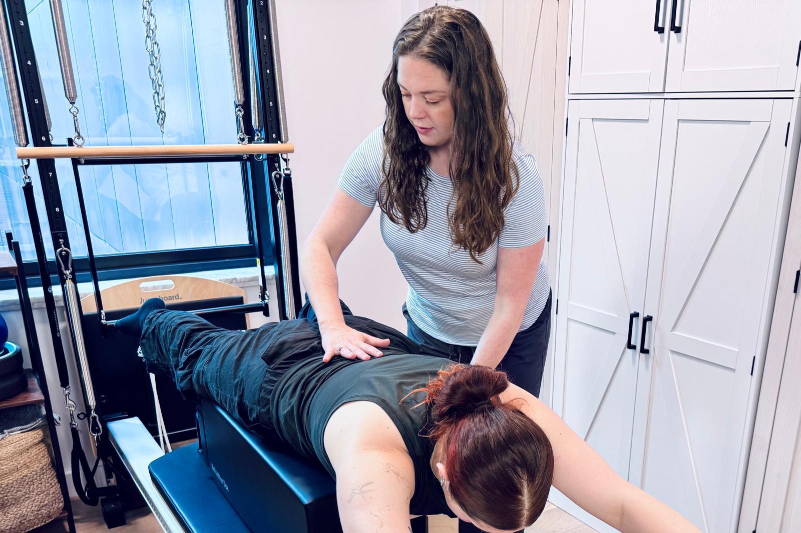 Pilates practitioner doing a side plank with their instructors guidance